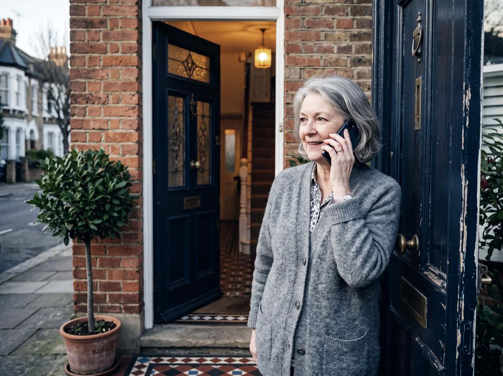 A woman at her front door on the phone, listening